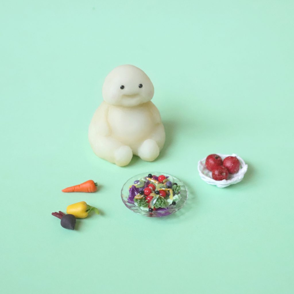 Miniature mascot sitting with healthy salad and fruits