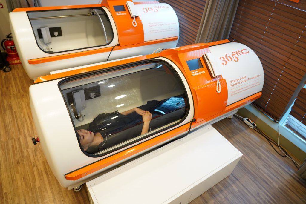 Patient receiving oxygen therapy inside 365mc hyperbaric tube after liposuction