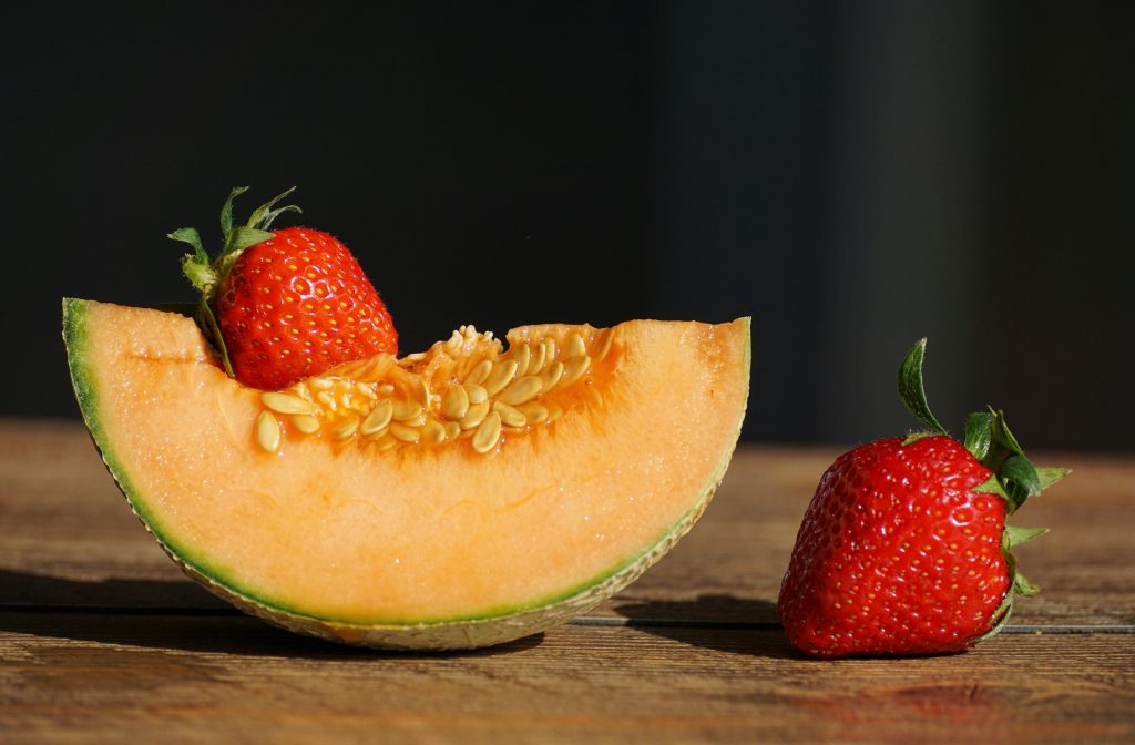 Fresh cantaloupe slice with ripe strawberries – perfect water-rich fruit for LAMS recovery